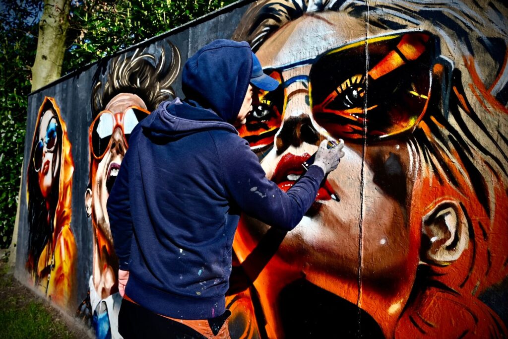 Theron tried something different, resulting in four unique characters with sunglasses. All the images were AI-generated and posted on Pinterest. Theron used these AI images as inspiration and painted them on his garden wall. He really enjoyed the experience and plans to create more in the future. Perhaps even on canvas. Would you be interested in owning a piece of this innovative art?