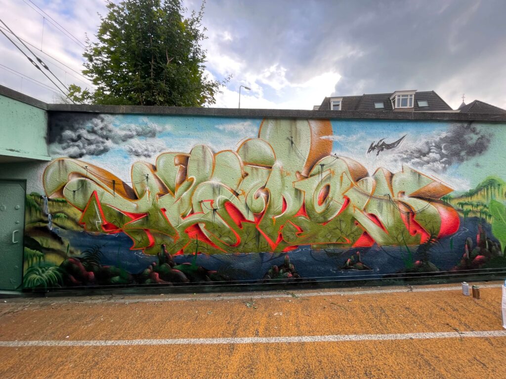 In the vibrant world of graffiti, where art and rebellion converge, a special chapter unfolds in the picturesque city of Roosendaal. The Loods, a renowned graffiti hall of fame, invited some of the most prominent names in the graffiti scene, including the talented Theron, to participate in an extraordinary social project: the transformation of the iconic Kadetunnel.
The Kadetunnel, saturated with history and memories, was in need of a fresh breath after years. Like an empty canvas, it patiently awaited to be brought to life by the imagination of these artists. The Loods in Roosendaal served as the epicenter of creativity, where spray cans acted as brushes, and graffiti as the medium to create a visual masterpiece.
With a shared vision to use art as a powerful instrument for societal change, Theron and his fellow artists immersed themselves in the jungle theme.