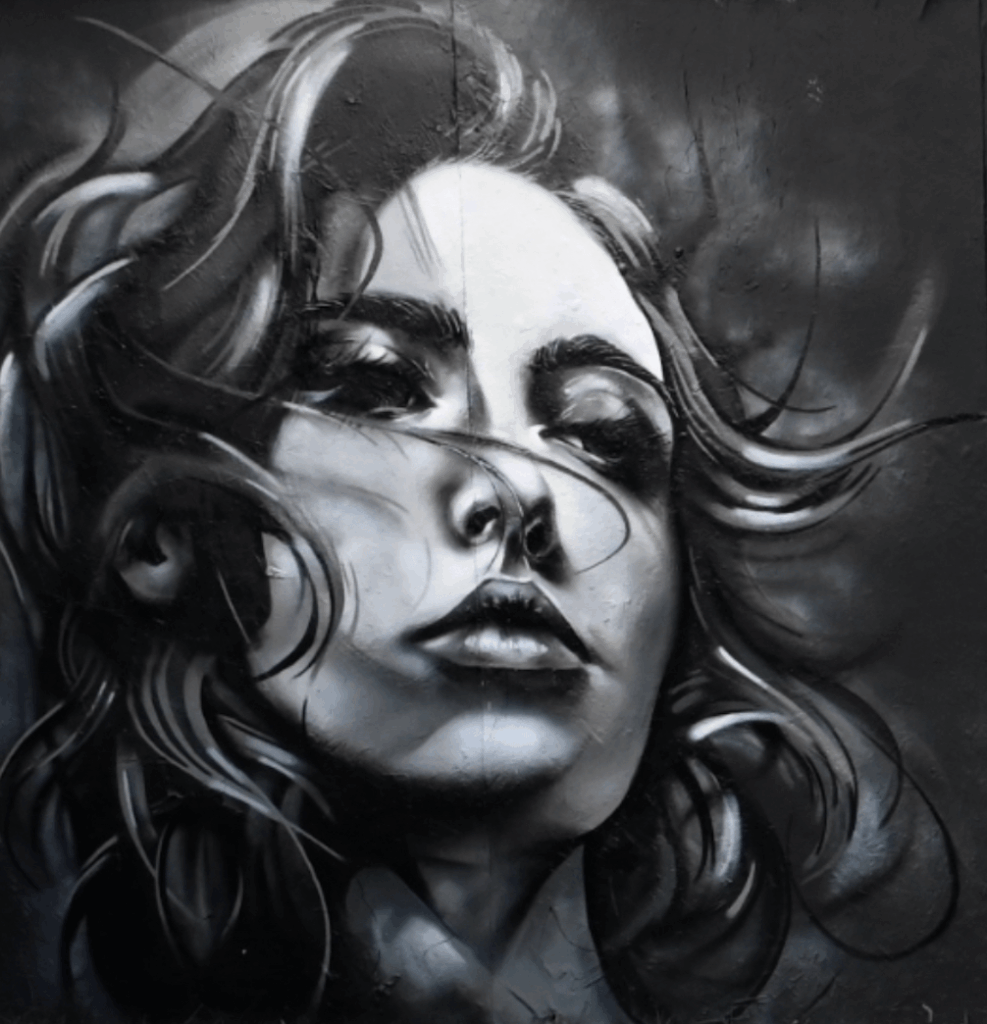 A detailed black and white graffiti mural of a woman's face with flowing hair, capturing a sense of emotion and movement. By Theron